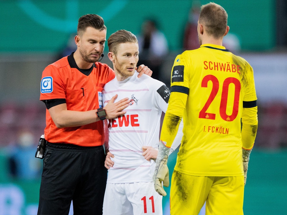 Schiedsrichter Daniel Schlager (l) tröstet Florian Kainz, der bei seinem Elfmeter den Ball zwei Mal berührt hatte, rechts steht Kölns Torwart Marvin Schwäbe.