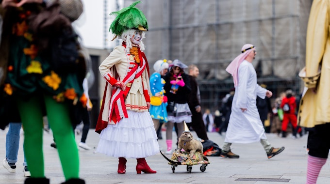 Eine Karnevalistin steht mit einem ausgestopften Murmeltier auf der Domplatte.