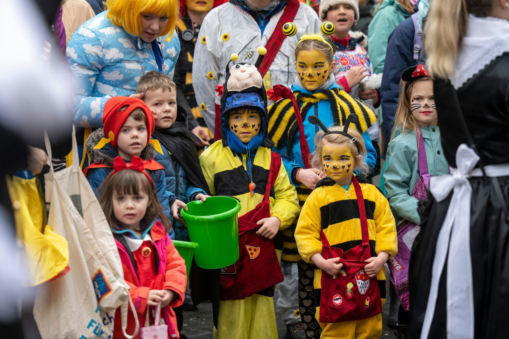 Kinder in einem Bienenkostüm stehen am Straßenrand.