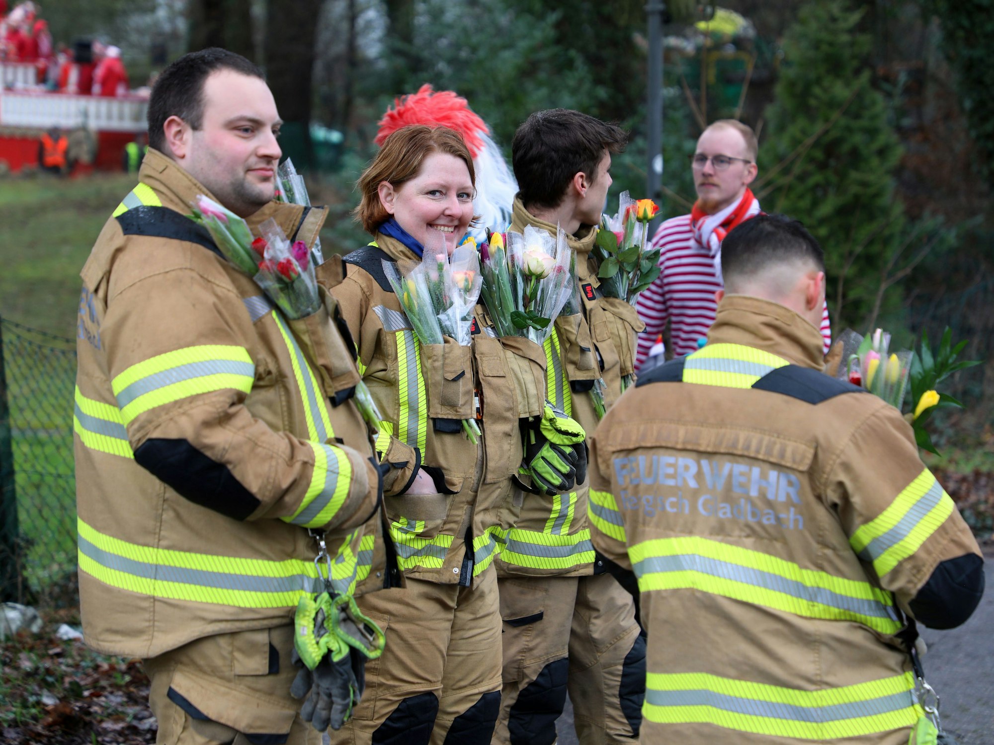 Feuerwehrkräfte stehen mit Blumensträußen am Zugrand.