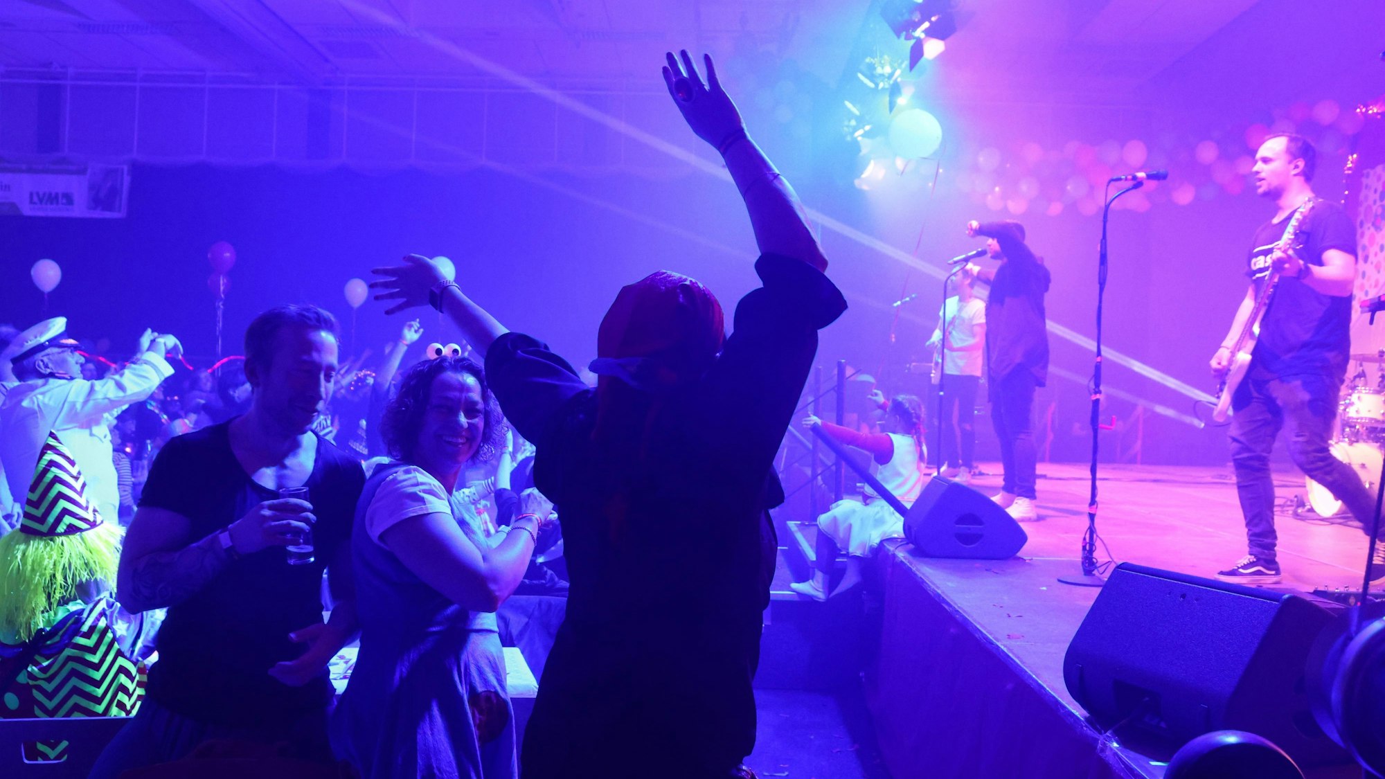 In einem Festzelt tanzt ein Mann vor einer Bühne, auf dem eine Band auftritt.