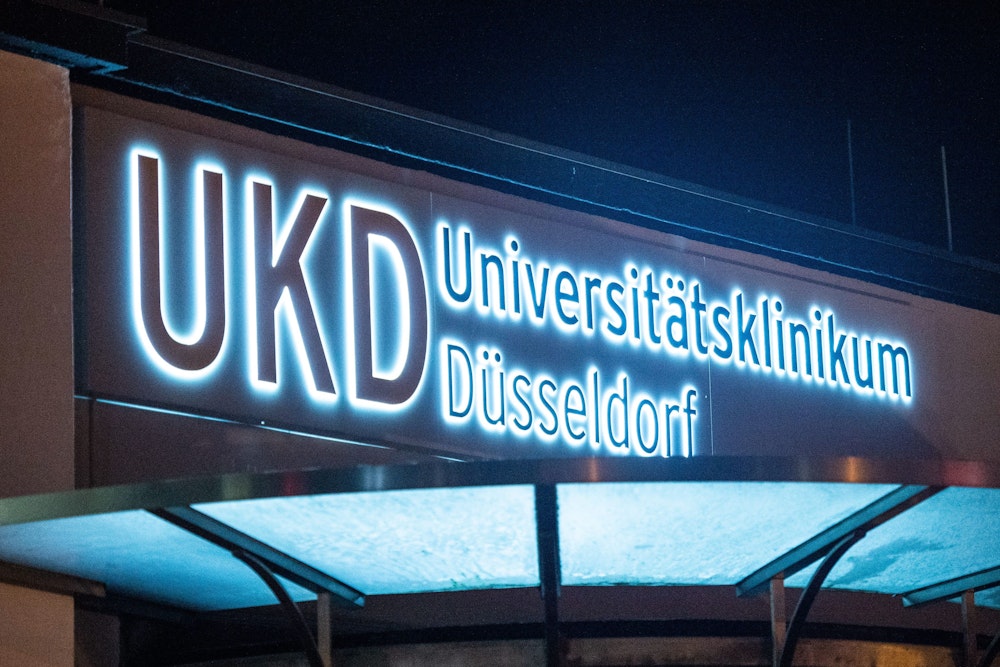 Das Logo des Universitätsklinikums Düsseldorf UKD leuchtet an einem Eingang des Krankenhauses. Zum dritten Mal weltweit ist es gelungen, einen krebskranken HIV-Patienten mithilfe einer Stammzellentransplantation von beiden Erkrankungen zu heilen.
