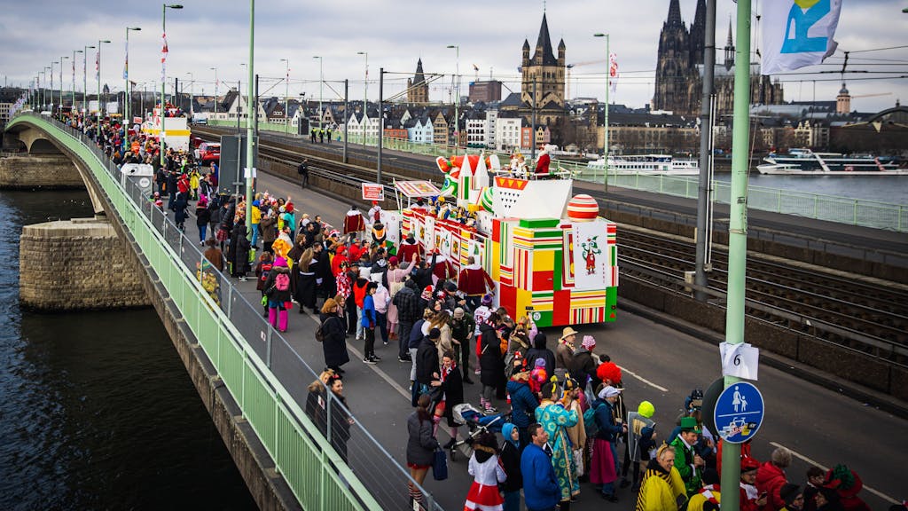 Eine Gruppe im Kölner Rosenmontagszug passiert die Deutzer Brücke, im Hintergrund der Kölner Dom.