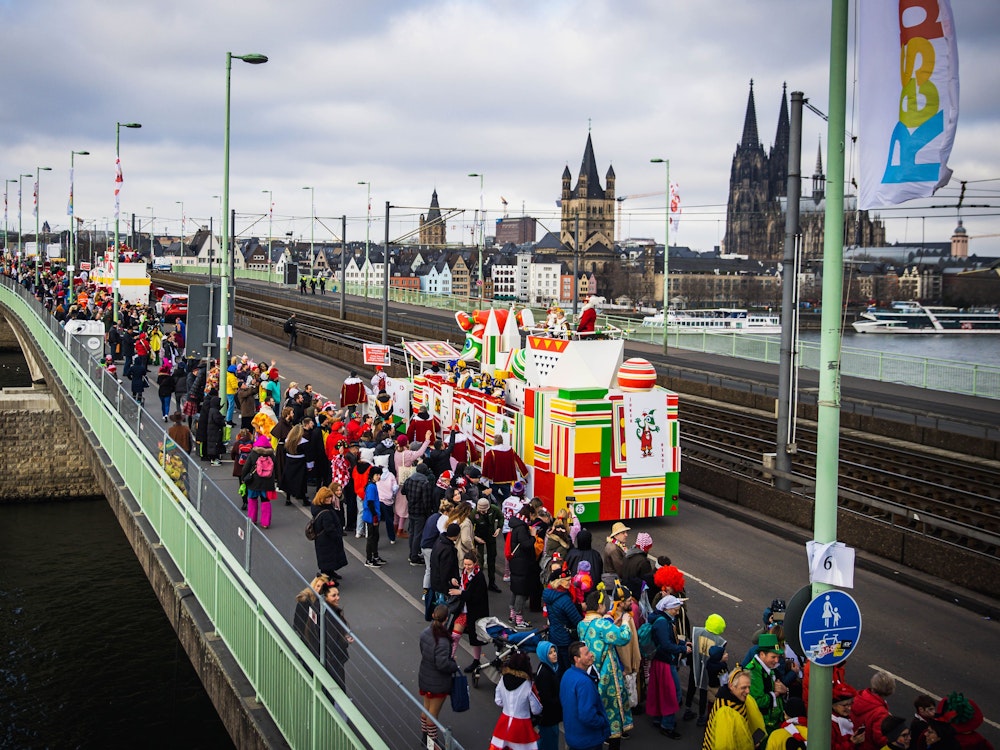 Eine Gruppe im Kölner Rosenmontagszug passiert die Deutzer Brücke, im Hintergrund der Kölner Dom.