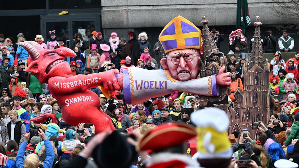 Ein Mottowagen zeigt den Teufel, der am Kölner Kardinal Woelki zerrt, der sich am Kölner Dom festklammert.&nbsp;