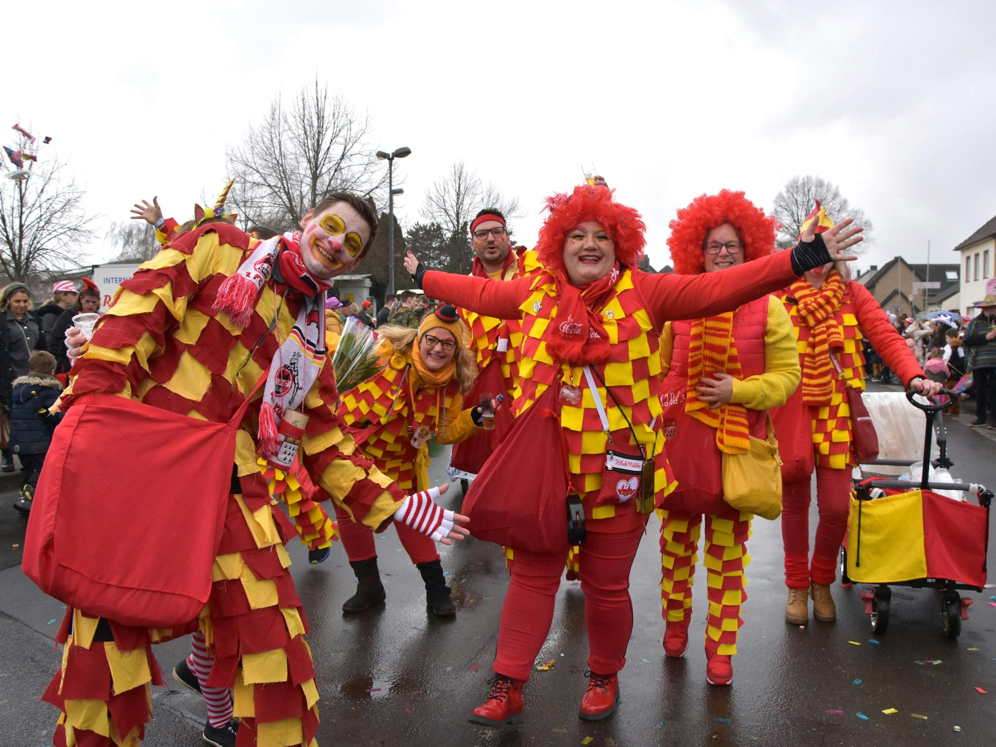 Kostümierte feiern in gelb-rot karierten Clowns-Anzügen.