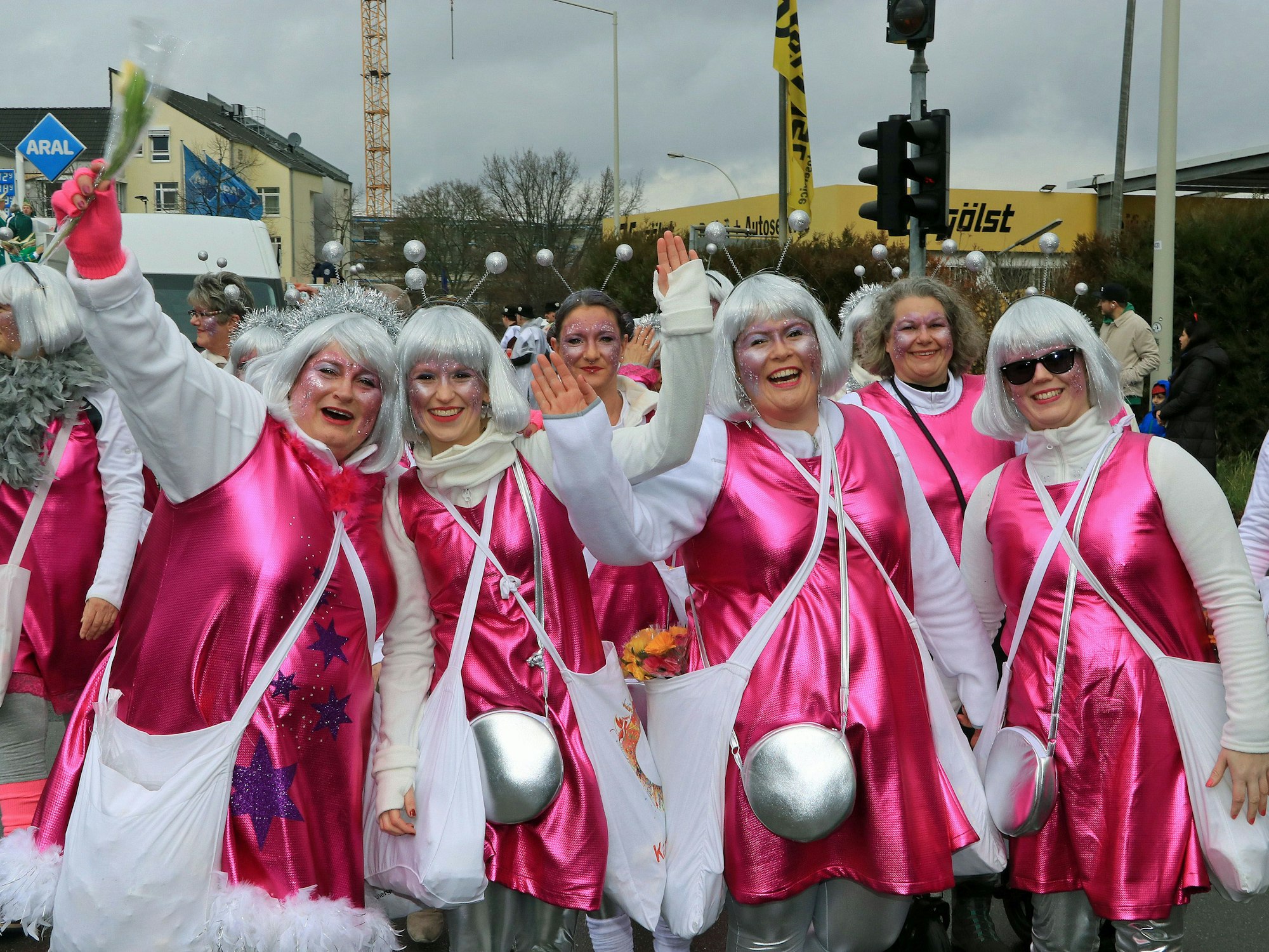 Frauen haben rosa Kostüme an, silberne Perücken auf.