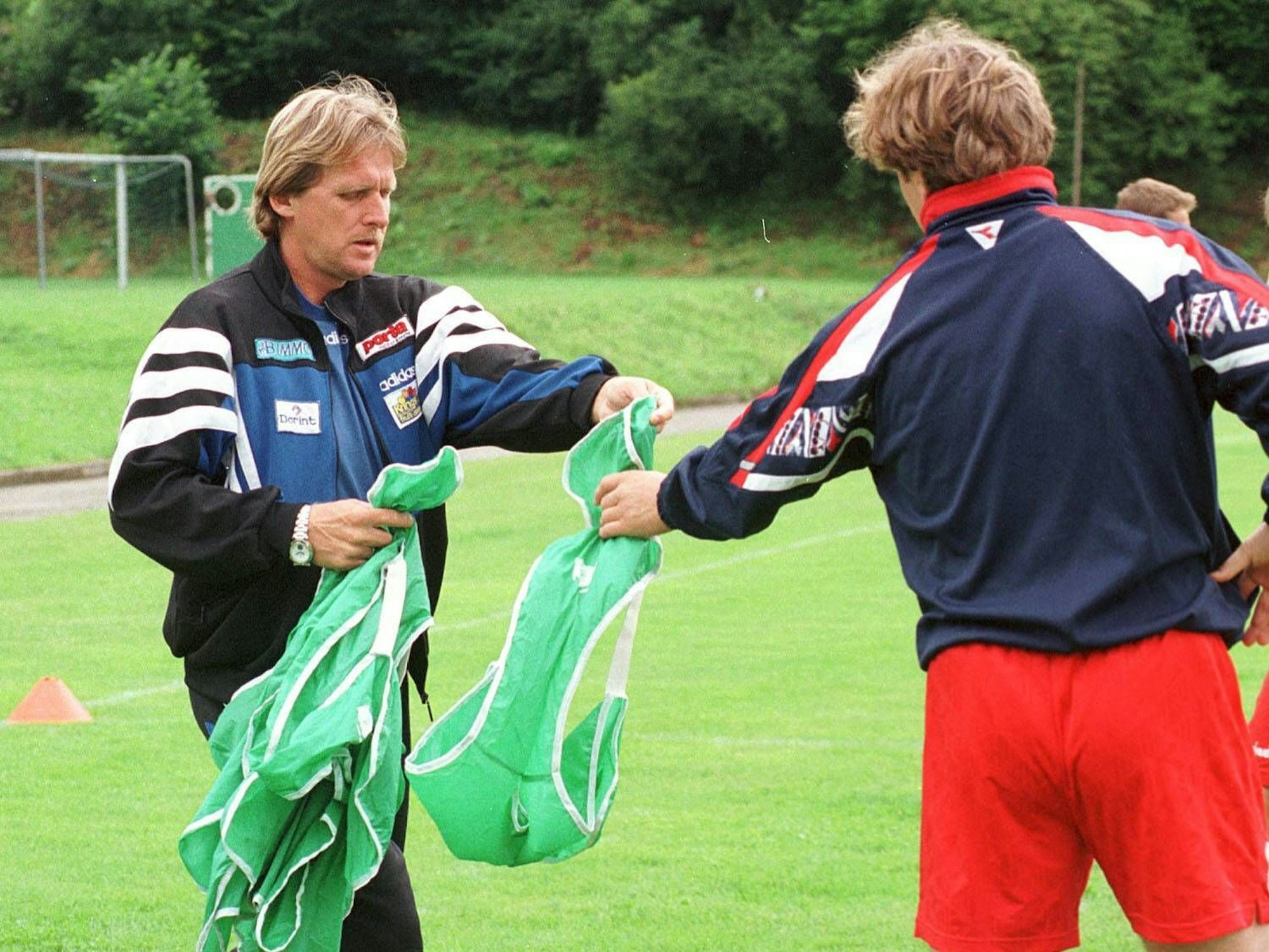 Trainer Bernd Schuster verteilt die Leibchen.
