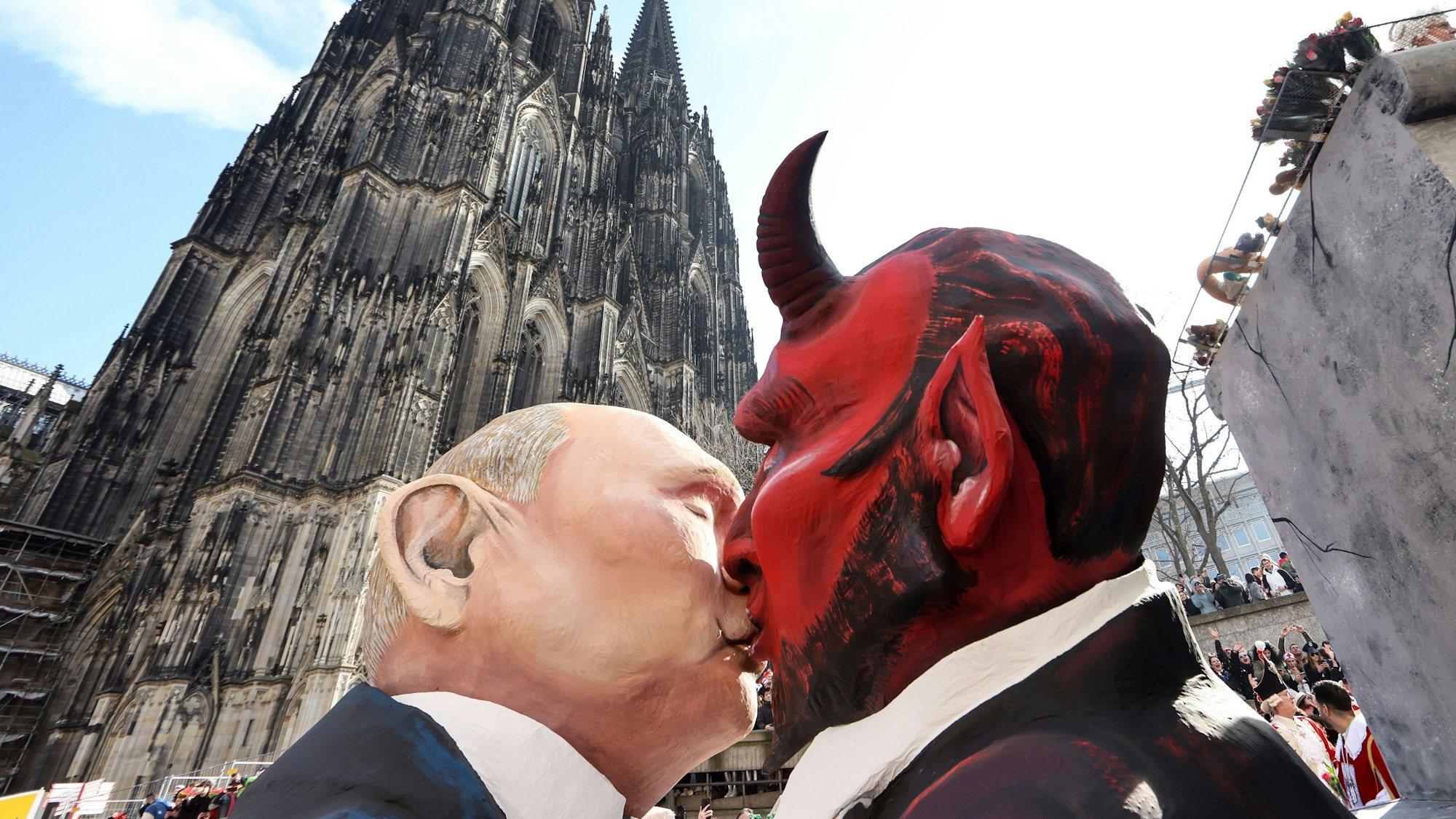 Der Mottowagen „Verkörperte Zitate“, dem Motto der Session von 1911, mit einer Darstellung des russischen Präsidenten Putin, der den Teufel küsst, fährt am Kölner Dom vorbei.