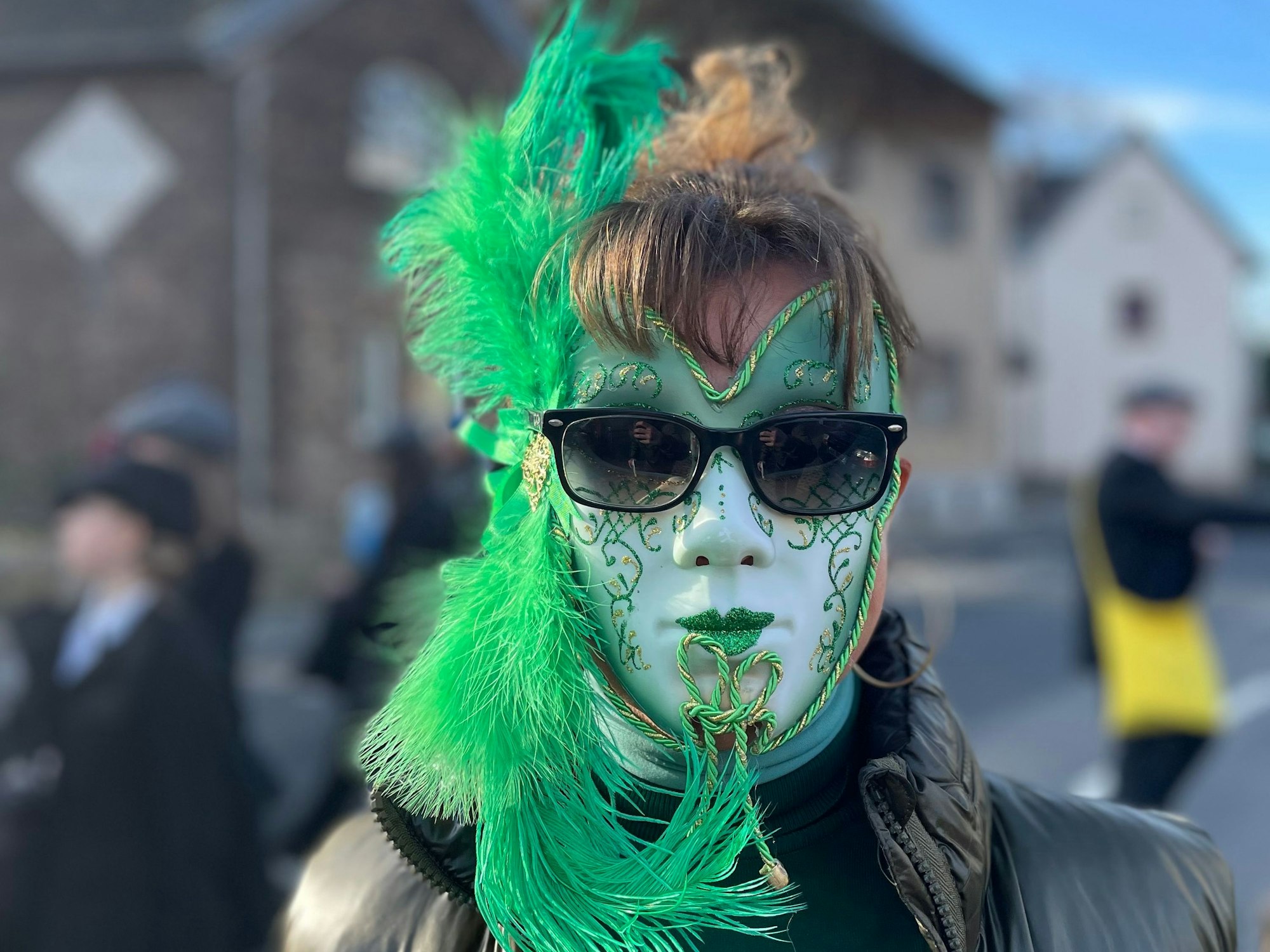 Eine Frau trägt eine aufwendig verzierte Maske bei einem Karnevalszug.