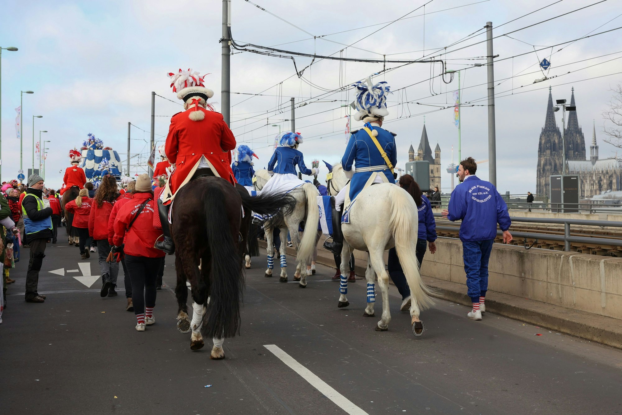 Pferde mit Reitern der roten und blauen Funken sind von hinten auf der Deutzer Brücke zu sehen.