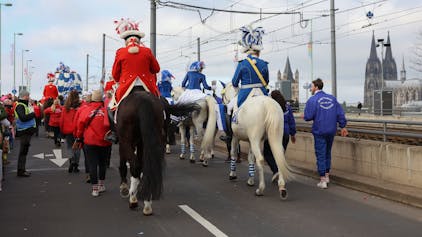 Karnevalisten reiten auf ihren Pferden über die Deutzer Brücke.