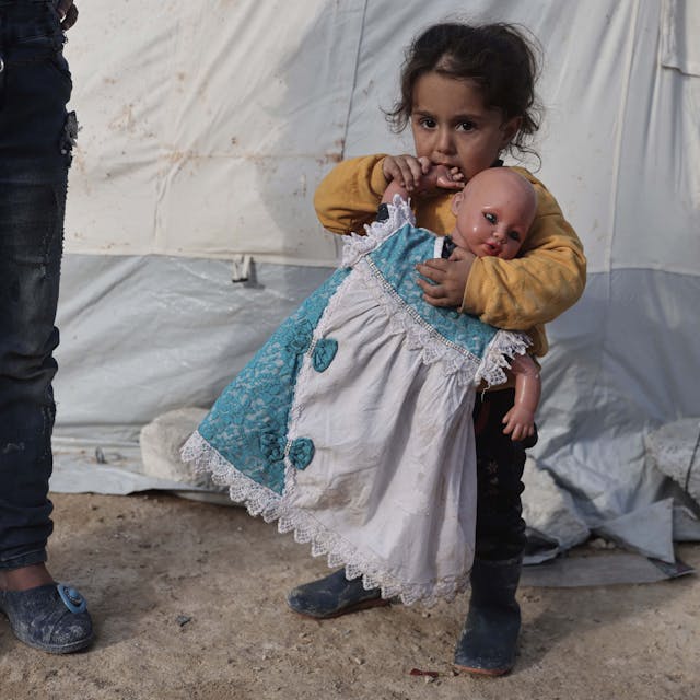 19.02.2023, Syrien, Salqin: Ein Kind hält eine Puppe in der Hand in einer Notunterkunft, die für die Opfer des Erdbebens an der türkisch-syrischen Grenze errichtet wurde. In Syrien sind bisher rund 5900 tote Menschen in Zusammenhang mit den verheerenden Beben gezählt worden.&nbsp;
