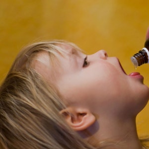Das Symbolfoto von 2009 zeigt ein Kleinkind mit geöffnetem Mund. Es bekommt flüssige Medizin aus einer braunen Glasflasche auf die Zunge geträufelt.