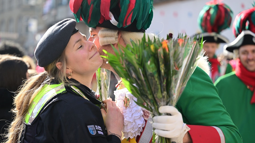 Eine Polizistin bekommt am Rande des Rosenmontagszuges ein Küsschen.