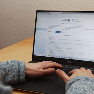 Eine Frau sitzt an einem Notebook und arbeitet an der Internetseite der Impf-Termninvergabe in Thüringen.