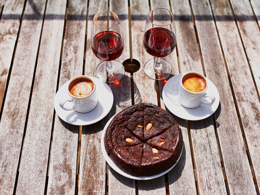 Kaffee, Wein und Kuchen stehen auf einem Holztisch.