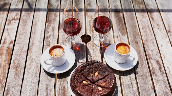 Kaffee, Wein und Kuchen stehen auf einem Holztisch.