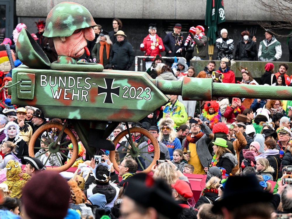 Ein Mottowagen mit der Aufschrift "Bundeswehr 2023" zeigt einen auf ein Fahrrad montierten Panzer.
