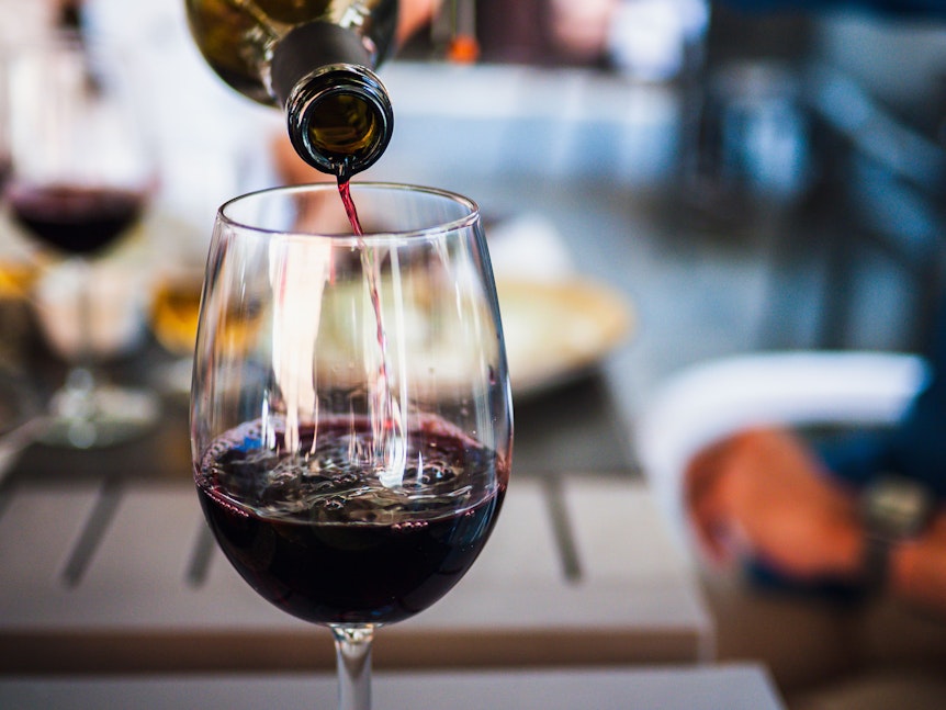 Aus einer Flasche wird Rotwein in ein Glas geschüttet.