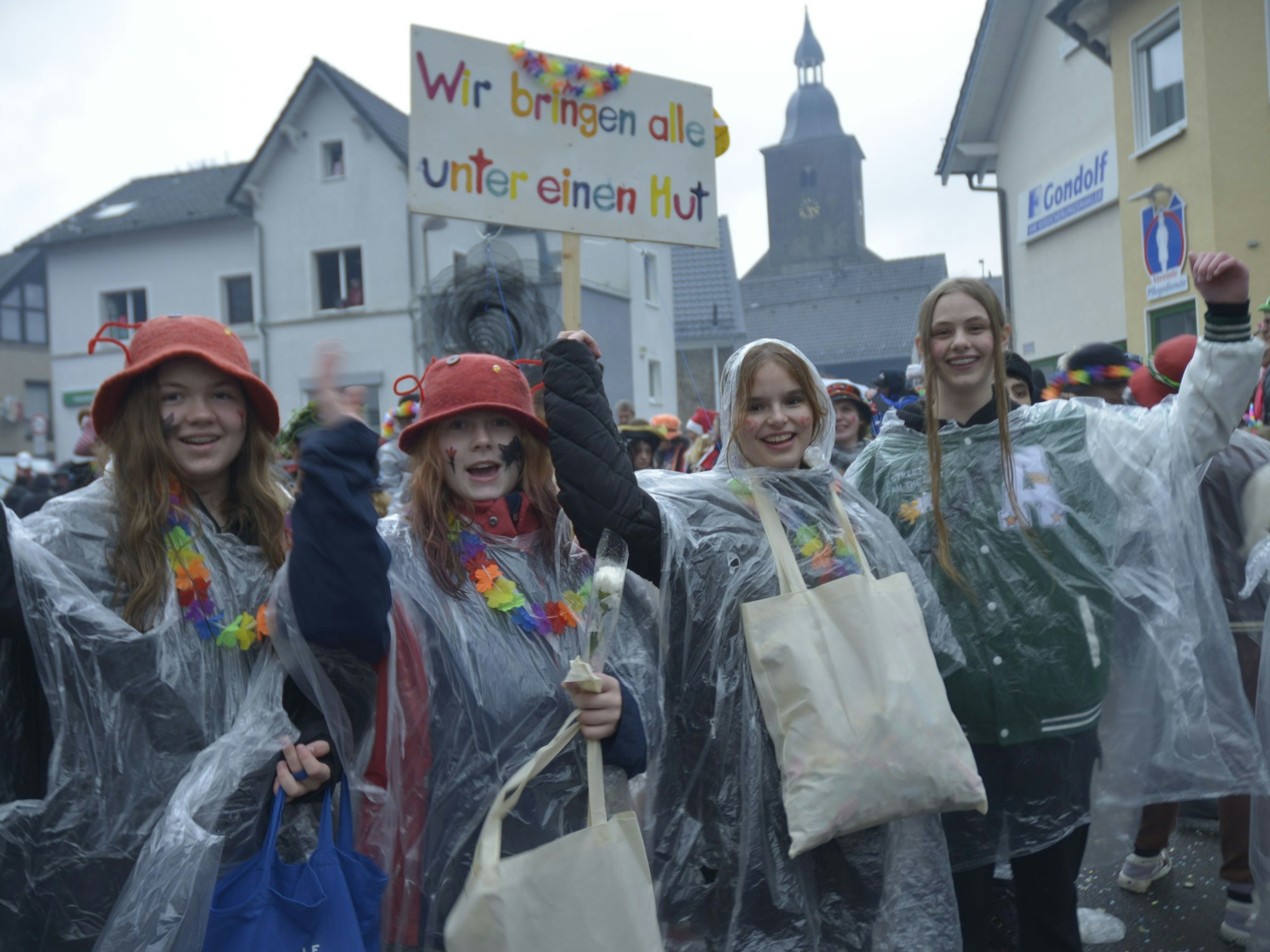 Vier verkleidete Frauen halten ein Schild hoch mit der Aufschrift „Wir bringen alle unter einen Hut“
