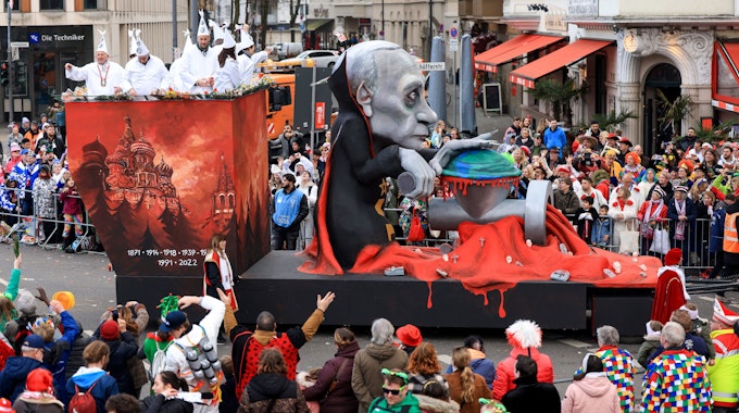 Russlands Präsident Wladimir Putin dreht die Welt auf einem Mottowagen des Kölner Rosenmontagszuges durch einen Fleischwolf.