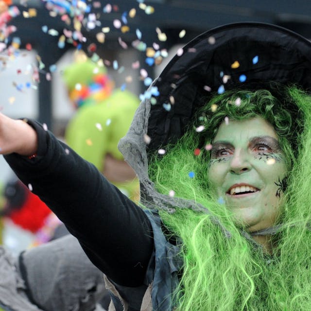 Eine Hexe mit grünen Haaren wirft mit Konfetti.&nbsp;
