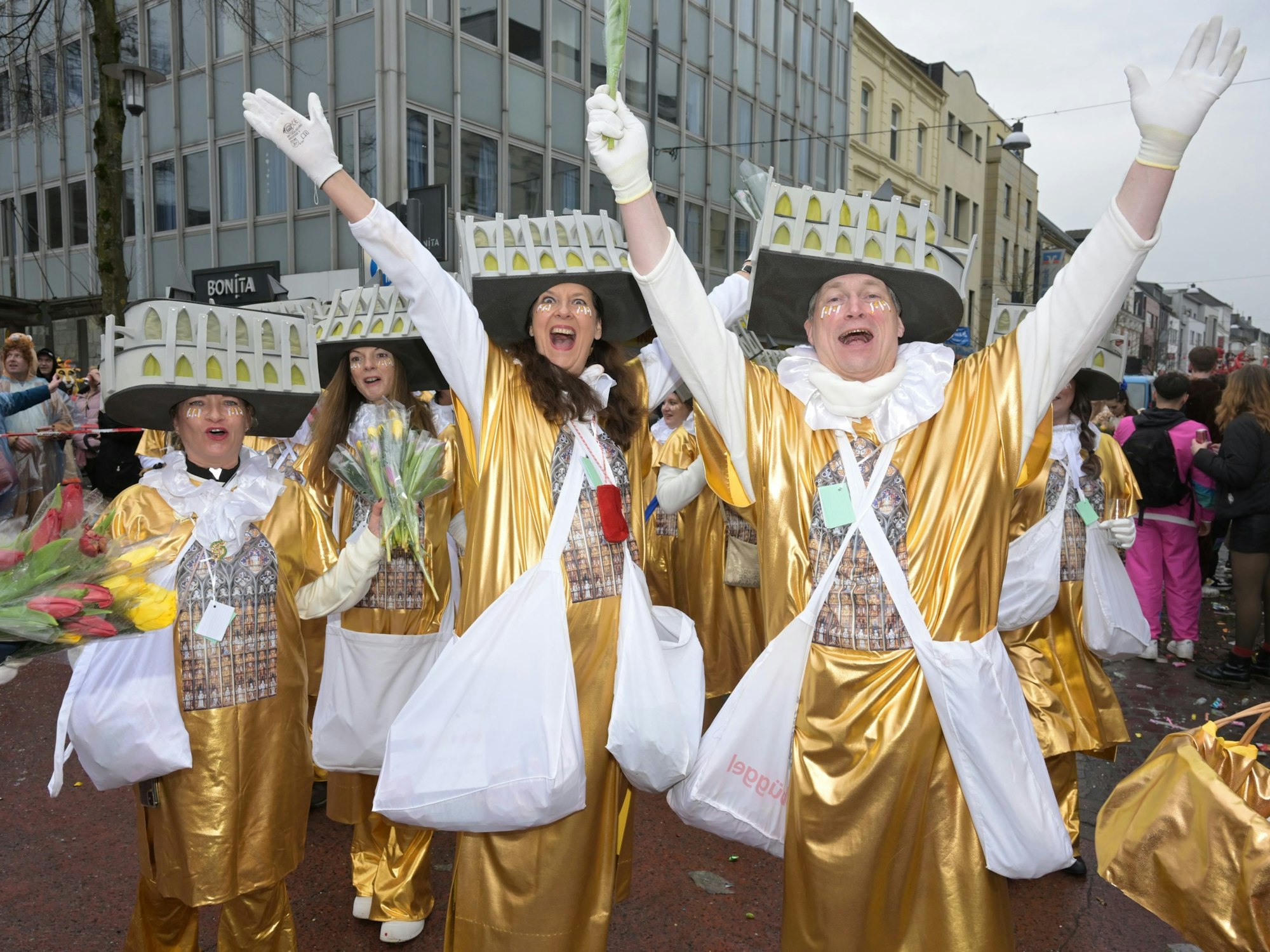 Eine Gruppe in goldenem Kostüm reißt die Arme in die Höhe.