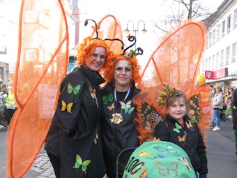 Zwei Frauen und ein Mädchen sind als Schmetterling verkleidet.