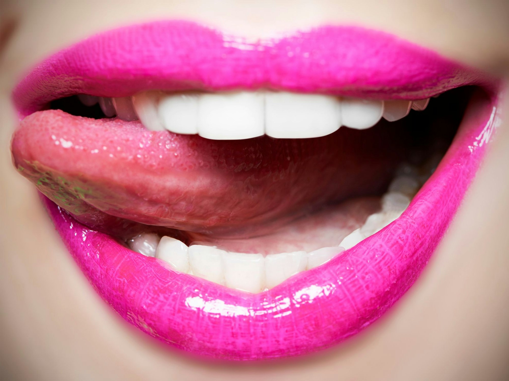 Junge Frau leckt sich über pink geschminkte Lippen
