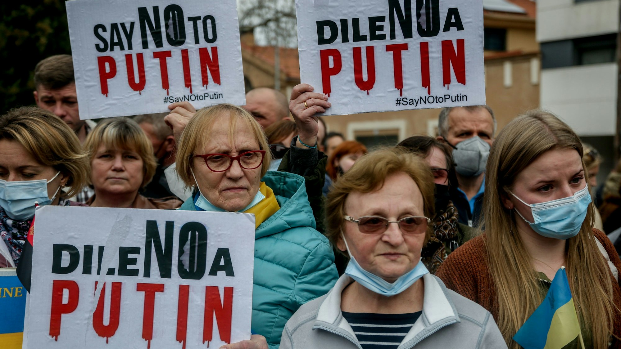 Demonstrantinnen und Demonstranten stehen mit Plakaten vor der russischen Botschaft und protestieren.