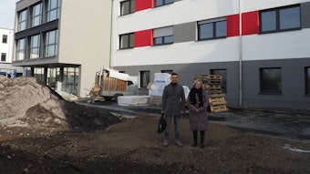 Daniel Tameh und Wiebke Herrmann stehen vor einem Gebäude auf einer Baustelle.