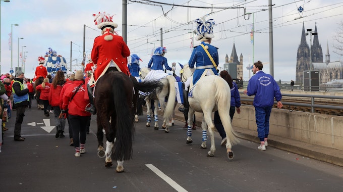 Funken reiten während des Rosenmontagszuges mit Pferden über die Deutzer Brücke.