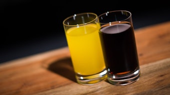 Ein Glas mit Cola steht neben einem Glas mit Orangenlimonade.