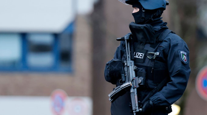 Ein Polizist mit Maschinenpistole bewacht die umliegenden Straßen, Dächer und Zufahrten.