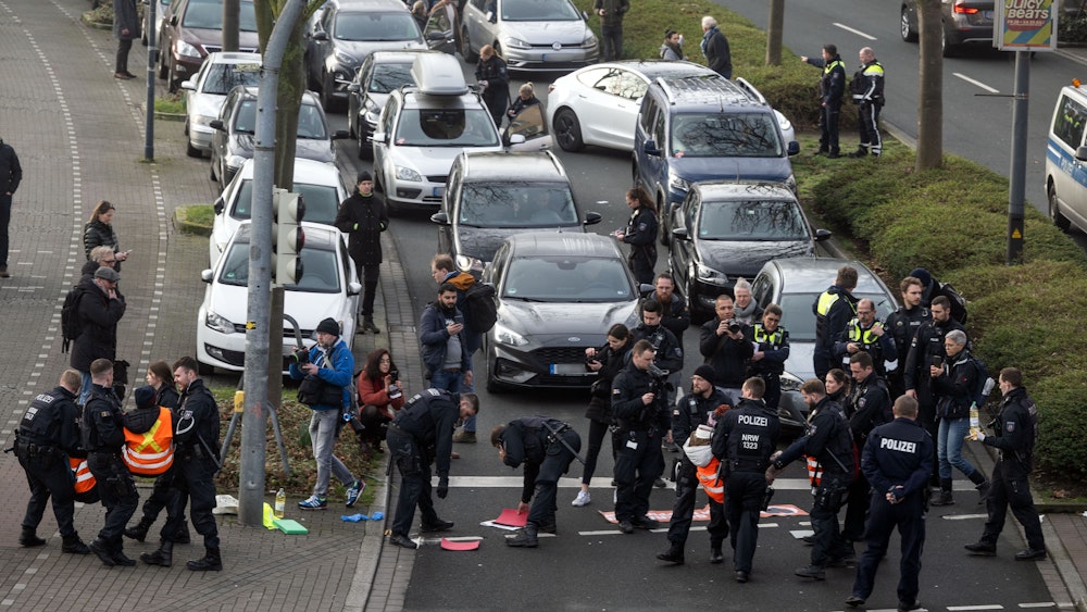 Protestanten der Gruppe „Letzte Generation“ werden an einer Hauptverkehrsstraße in Dortmund von Polizisten weggetragen, nachdem sie sich teilweise auf dem Asphalt festgeklebt hatten.