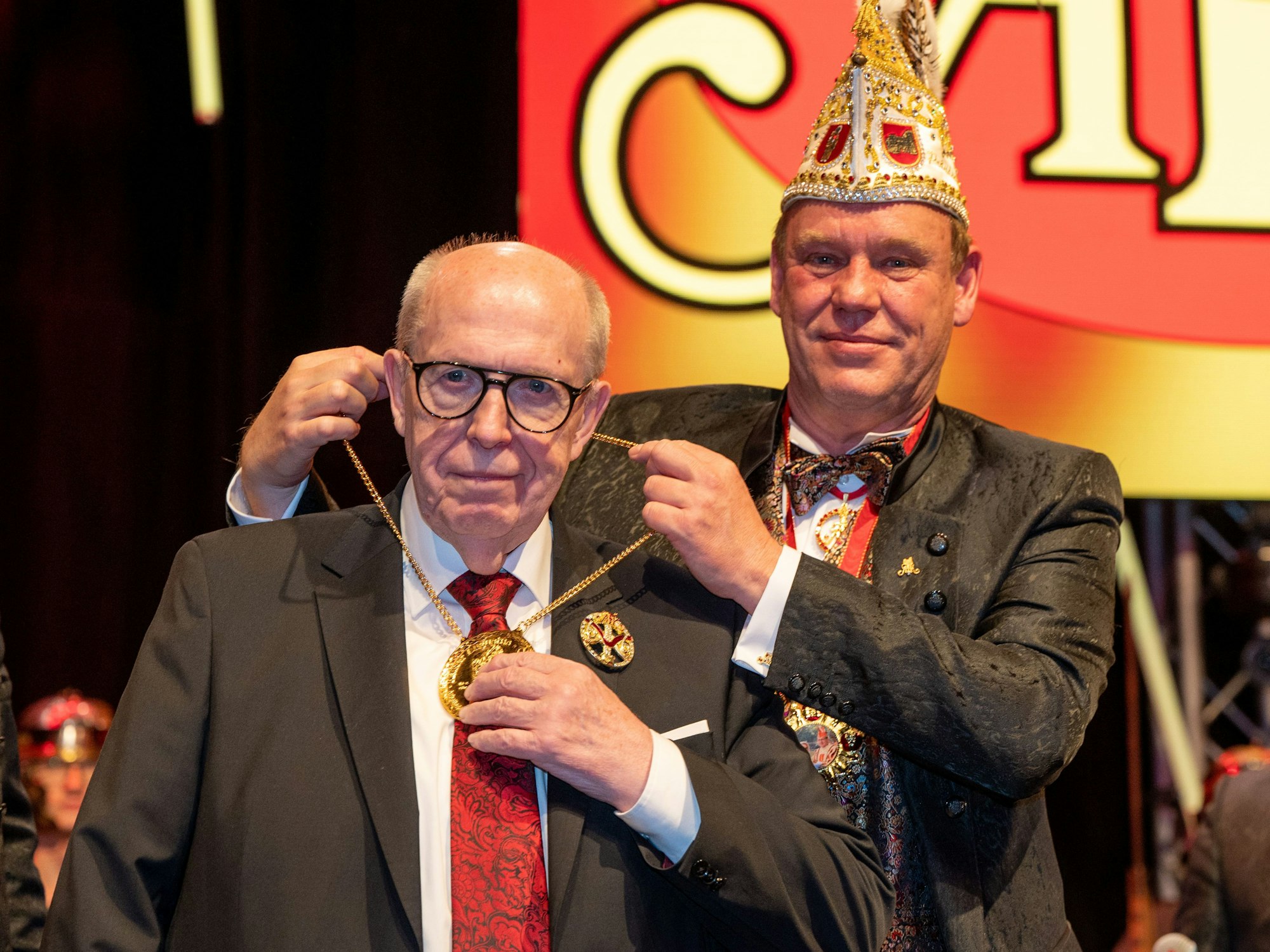 Andreas Peters (r.), Präsident der Arbeitsgemeinschaft Trierer Karneval, legt Reiner Calmund einen Orden um den Hals.