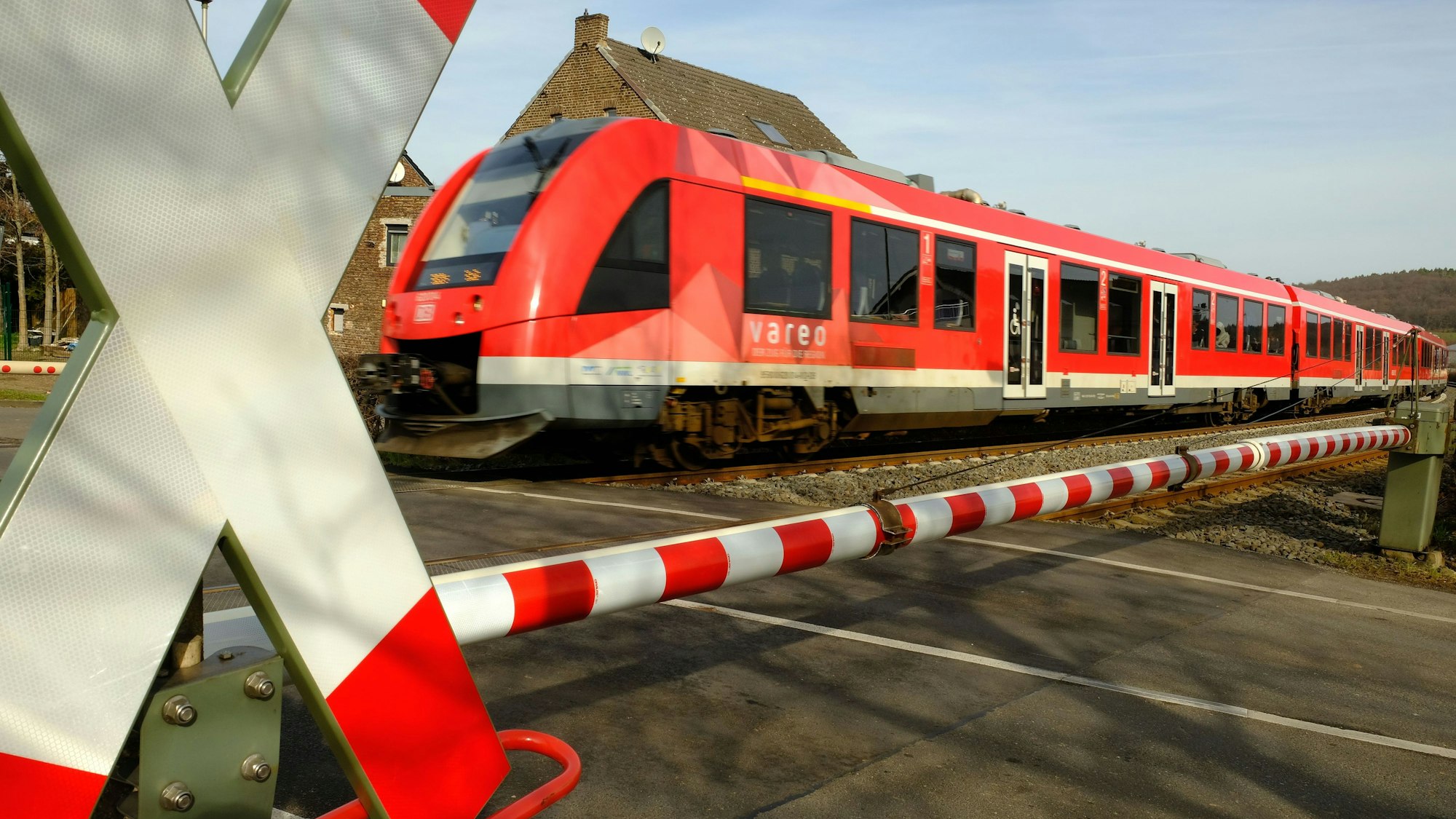 Das Bild zeigt einen Zug, der den Bahnübergang in Satzvey passiert.