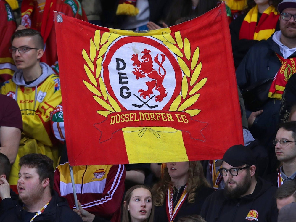 Eishockey-Fans der DEG halten ein Banner mit dem Schriftzug und Logo der DEG hoch.