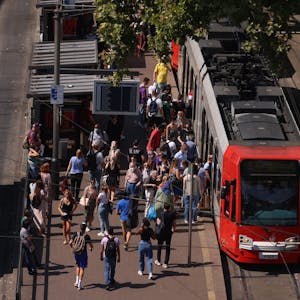 Zu sehen sind eine Stadtbahn und ein Bus der KVB sowie eine große Menschenansammlung am Kölner Neumarkt.