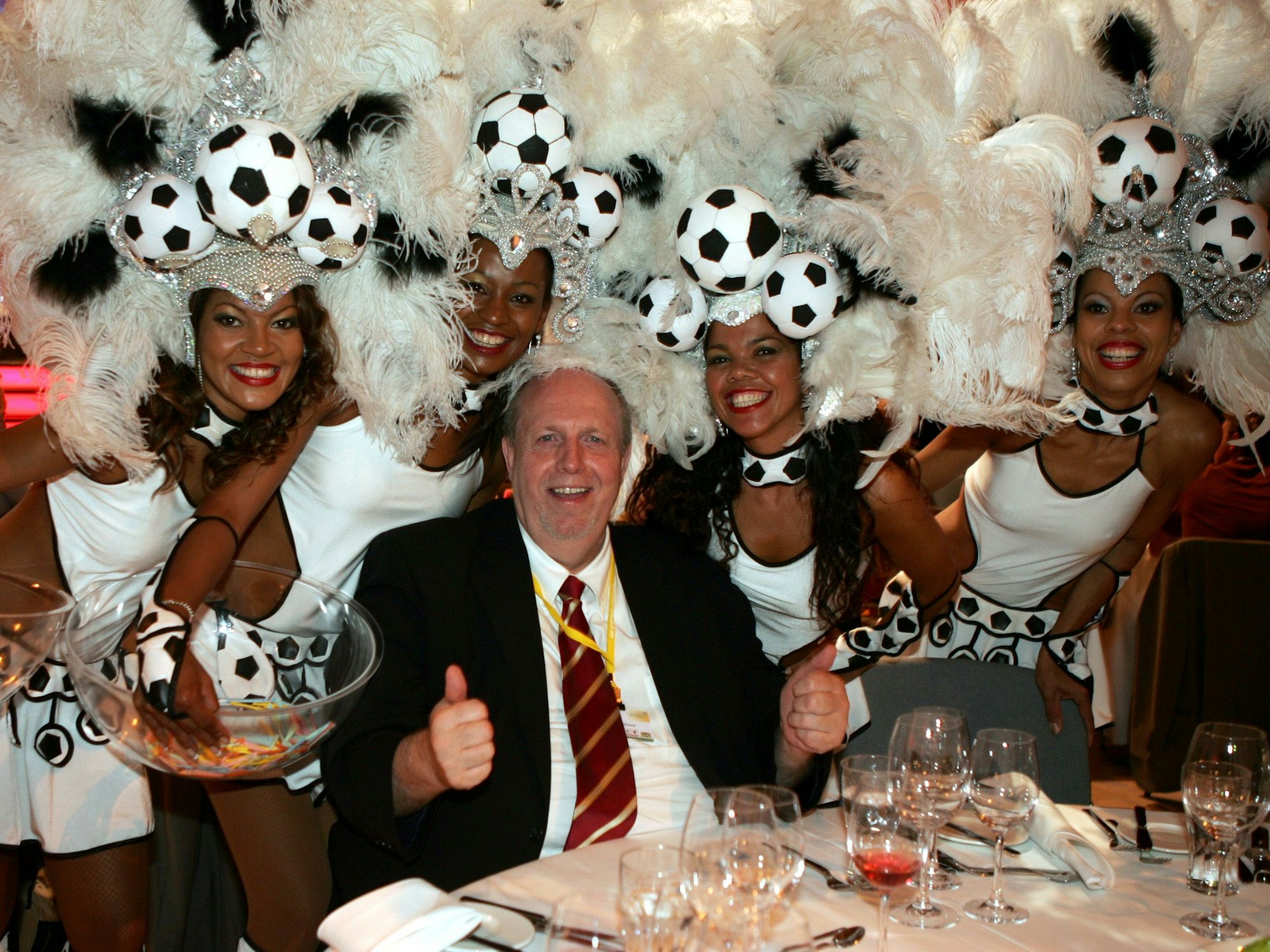 Reiner Calmund posiert mit vier Brasilianerinnen in Fußball-Kostümen für die Kamera.