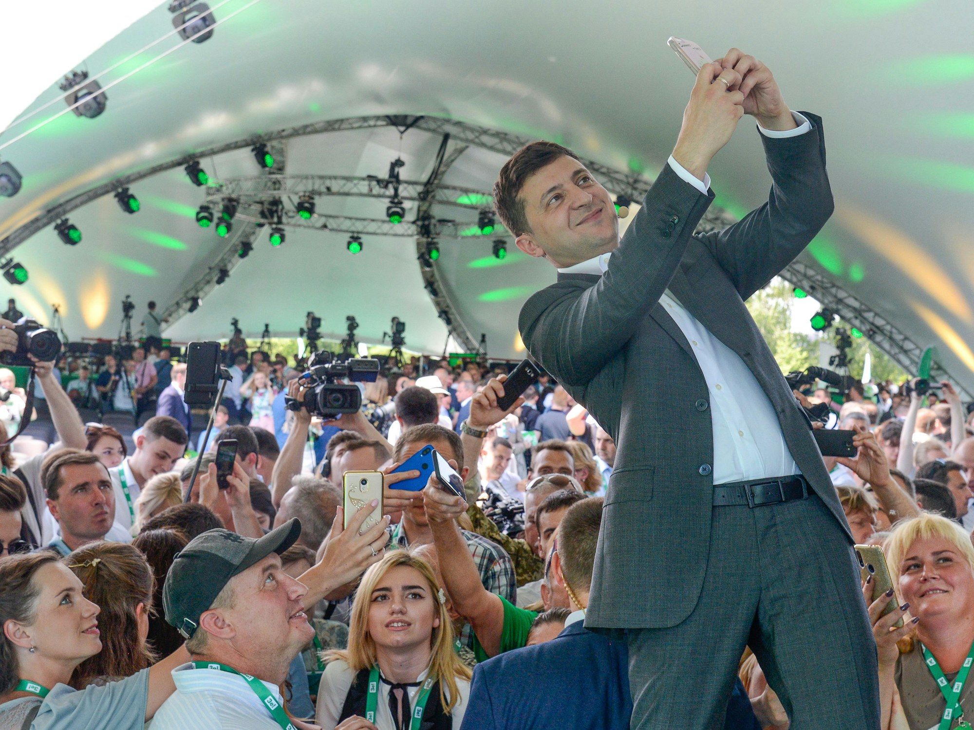 Das Foto von 2019 zeigt den ukrainischen Präsidenten Wolodymyr Selenskyj, wie er in einem großen Zelt vor vielen Menschen steht und mit dem Handy ein Selfie von sich und der Menge macht.