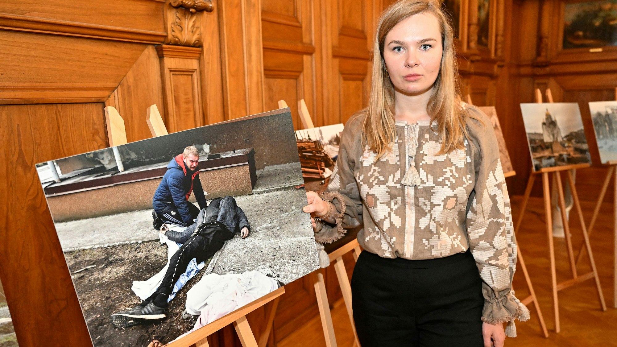 Alina Saraniuk aus Butscha hält ein Bild der bewegenden Ausstellung über die russischen Gräueltaten von Butscha im Bergisch Gladbacher Ratssaal.