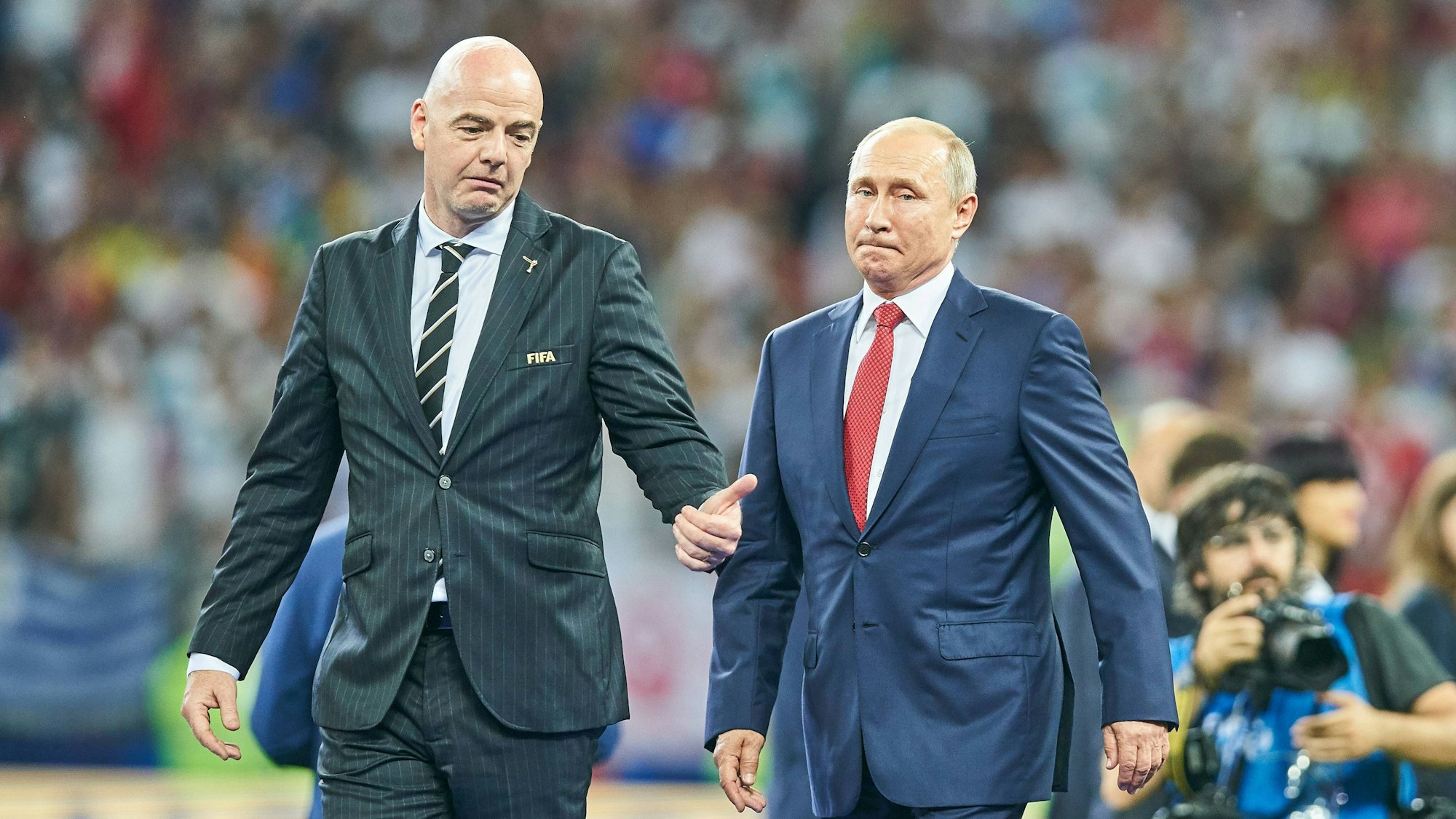 Fifa-Präsident Gianni Infantino (l.) und Wladimir Putin laufen nebeneinander auf dem Rasen des Luzhniki Stadion in Moskau nach dem Finale der Fußball-Weltmeisterschaft 2018 in Russland. Infantino und Putin tragen Anzüge und bereiten sich auf die Siegerehrung vor.