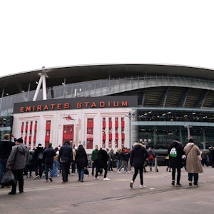 Das Emirates Stadium ist seit 2006 die Heimstätte des Premier-League-Vereins FC Arsenal. Das Foto zeigt das Stadion von außen am 11. Februar 2023, dem Tag des Arsenal-Heimspiels gegen Brentford. Fans überqueren den Vorplatz des Stadiums in Winterkleidung.