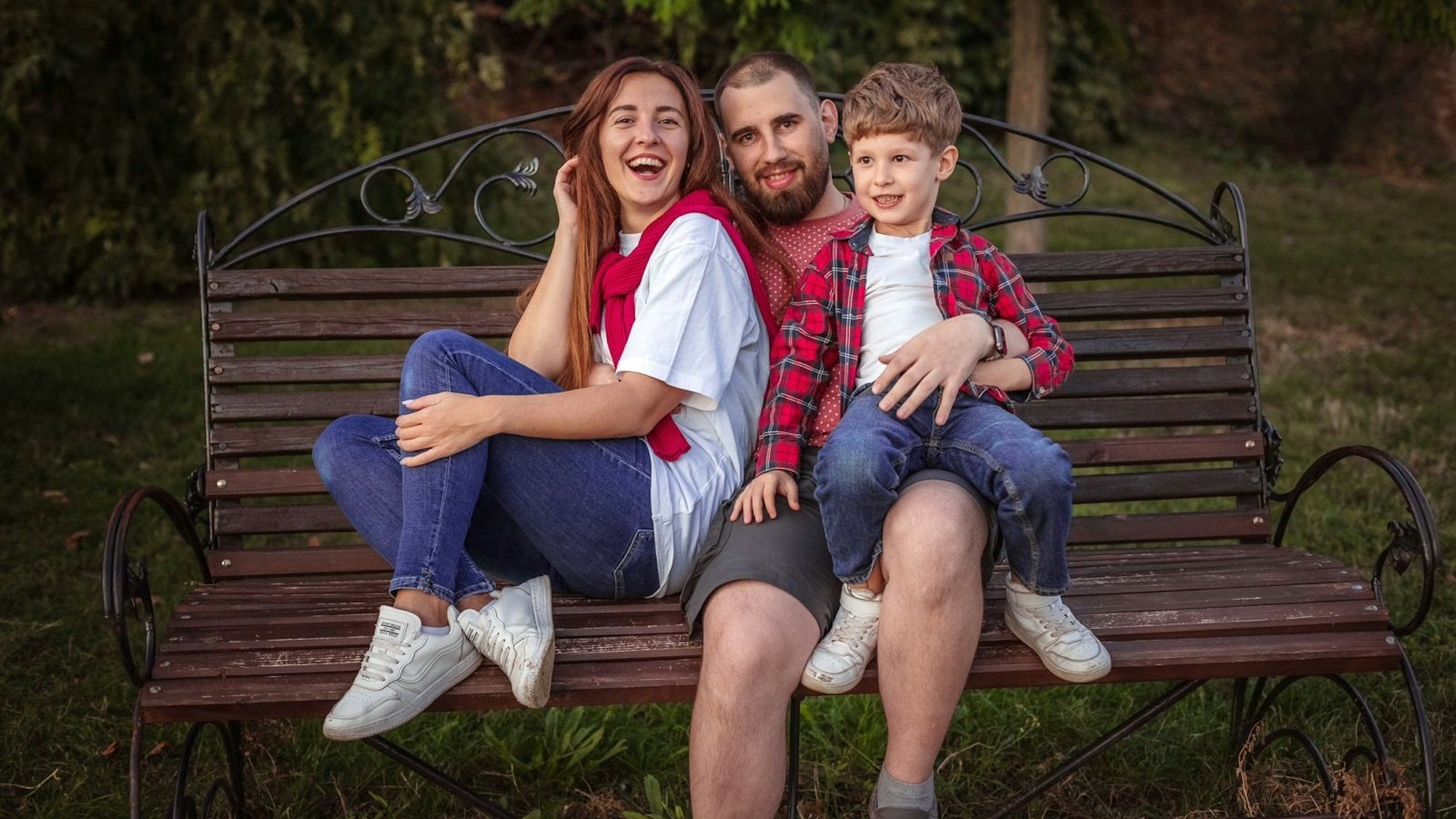 Olga mit Ehemann und Sohn in Kiew. Sie sitzen auf einer Bank.