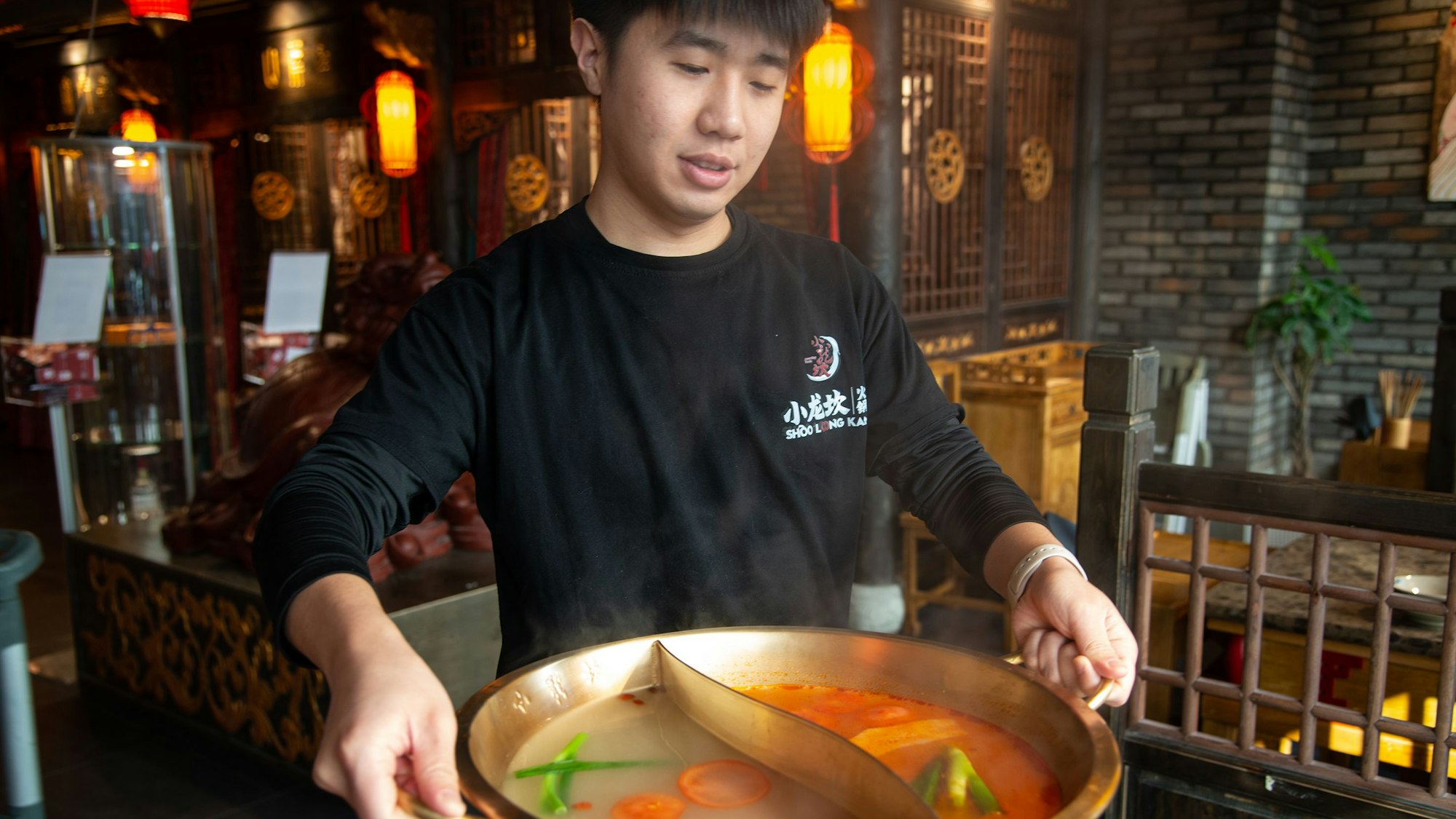 Der Mitarbeiter Jiachen Wong im Xiao Long Kan Hotpot in Düsseldorf bringt die heiße Sauce an
den Tisch.