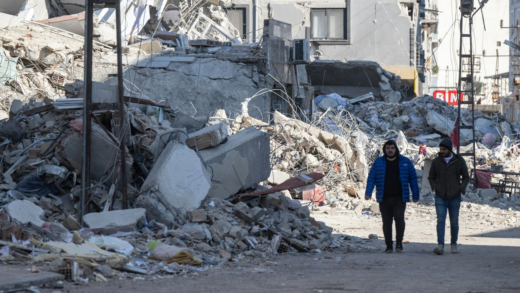 Zwei Männer gehen durch Trümmer in der Innenstadt von Kirikhan.