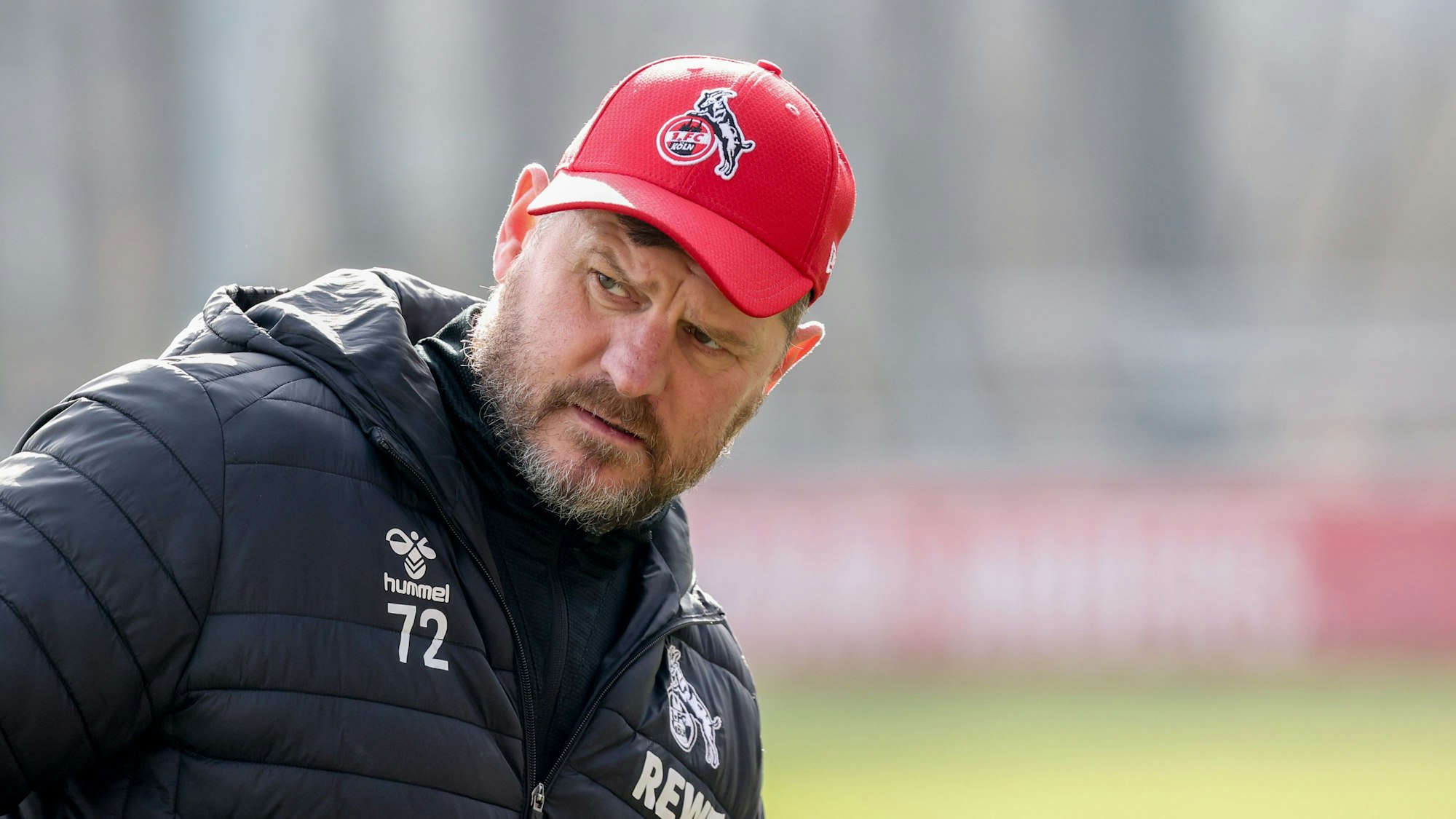 Steffen Baumgart auf dem Trainingsplatz, der Trainer des 1. FC Köln trägt eine rote Kappe und schaut skeptisch. Der 51-Jährige muss nach Verletzungen und Krankheitsfällen in seiner Mannschaft improvisieren.