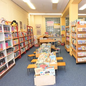 Zu sehen sind Bücherregale sowie Lesetische für Kinder und Erwachsene.